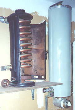 A Ruud sidearm heater sits with door open and coils exposed, next to a white Wesix Electric heate